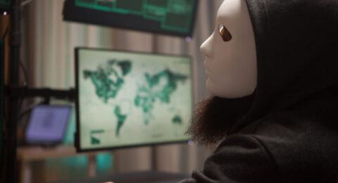 Bearded hacker with a hoodie wearing a white mask